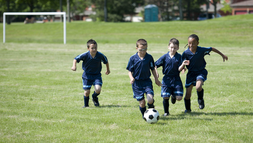 Hyväntuuliset pojat pelaavat jalkapalloa.