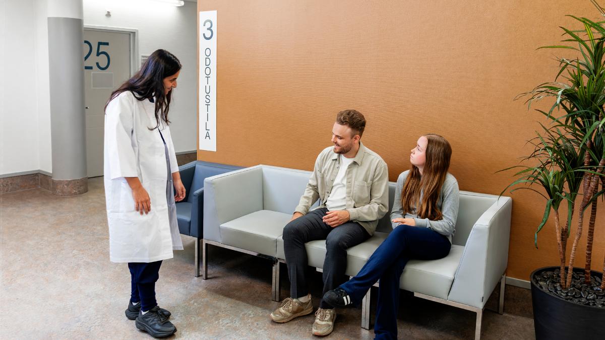 Lääkäri juttele isän ja tämän tyttären kanssa terveysaseman odotusaulassa.