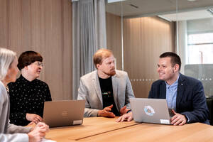 Kuvassa on muutama ihminen neuvottelemassa pöydän ympärillä.