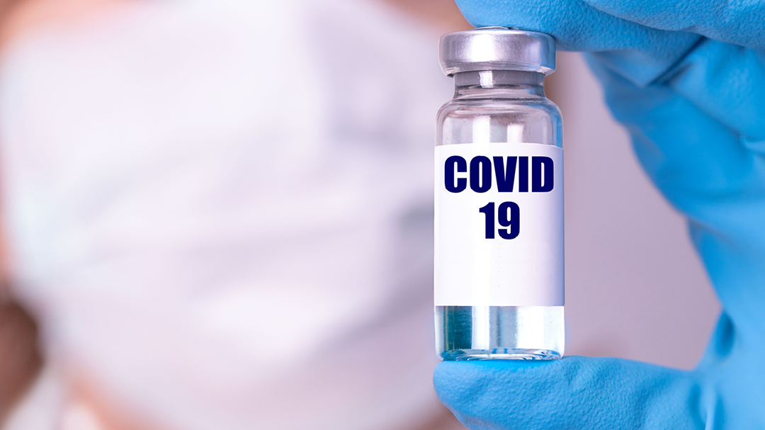 Kuvassa on rokotelääkepullo, jossa lukee covid-19.