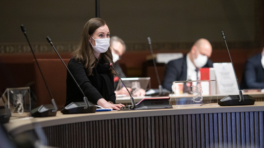 Pääministeri Marin maski kasvoillaan neuvottelupöydän äärellä Säätytalon salissa